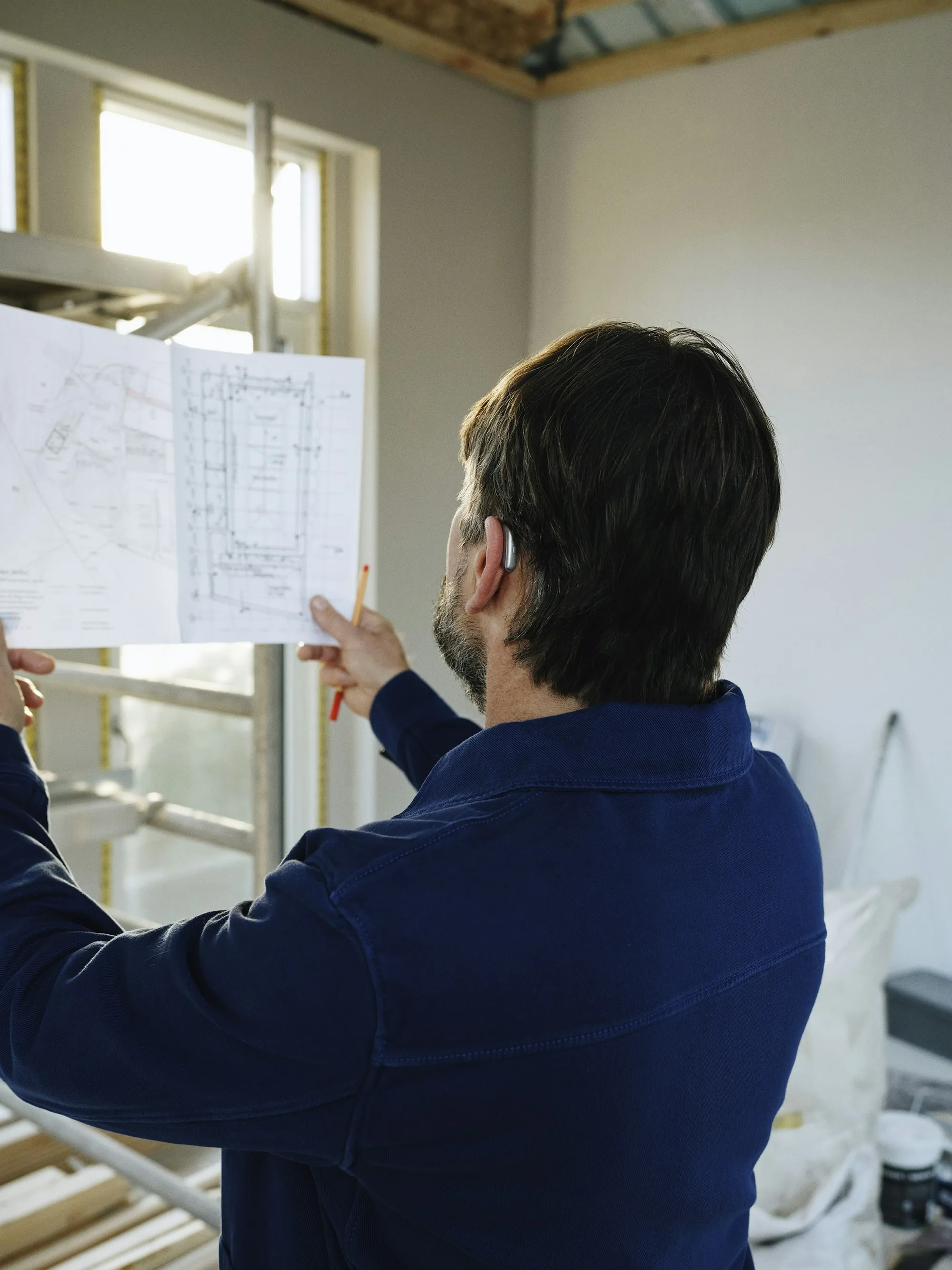 Project lead holding up floor plans inside a room under renovation