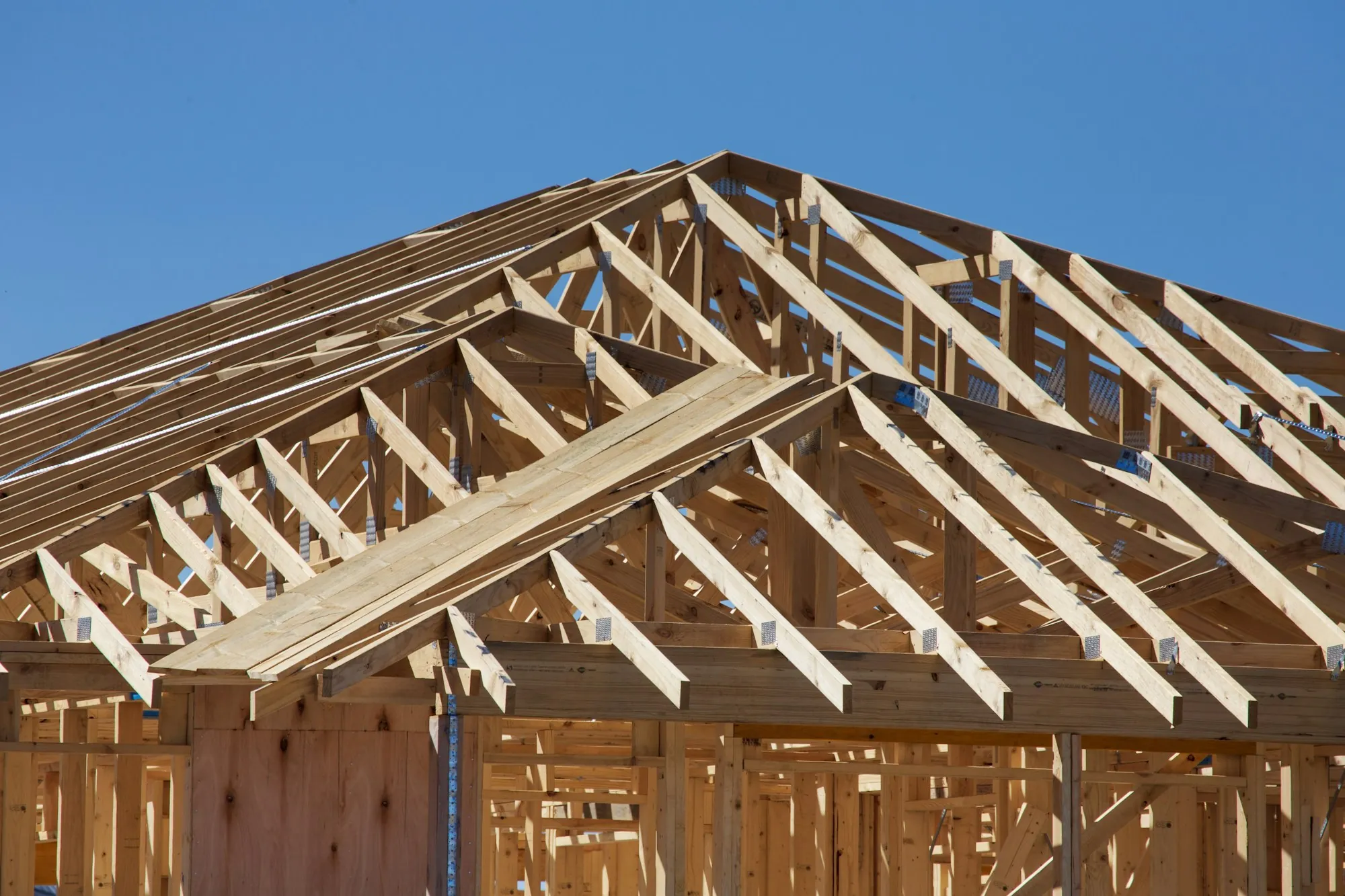 Roof trusses set on a newly framed house against a blue sky