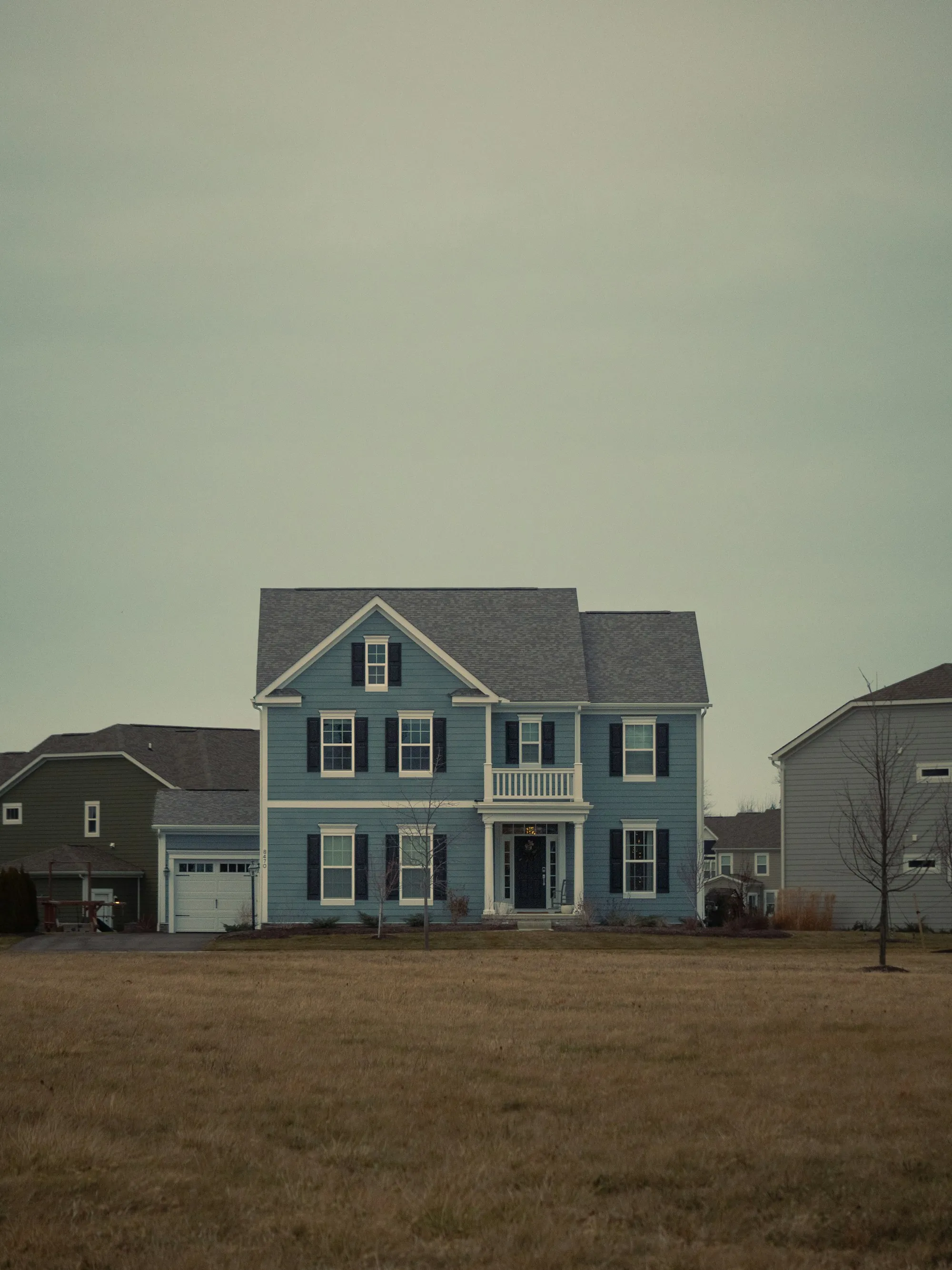 Blue two-story home with white trim and a wide front lawn