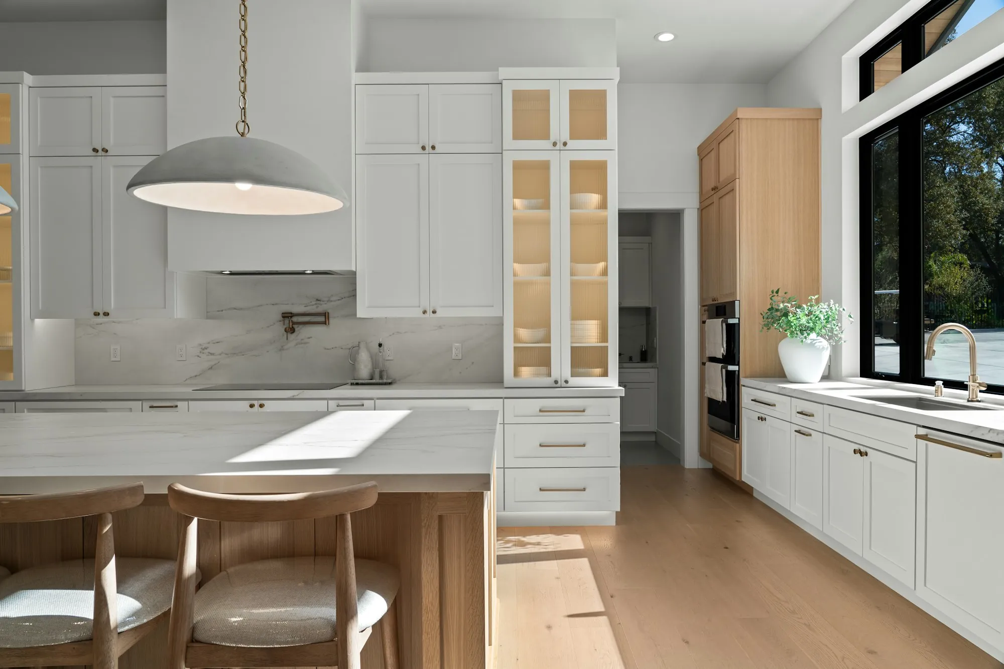 Remodeled kitchen with white shaker cabinets, a wood island and a large window over the sink