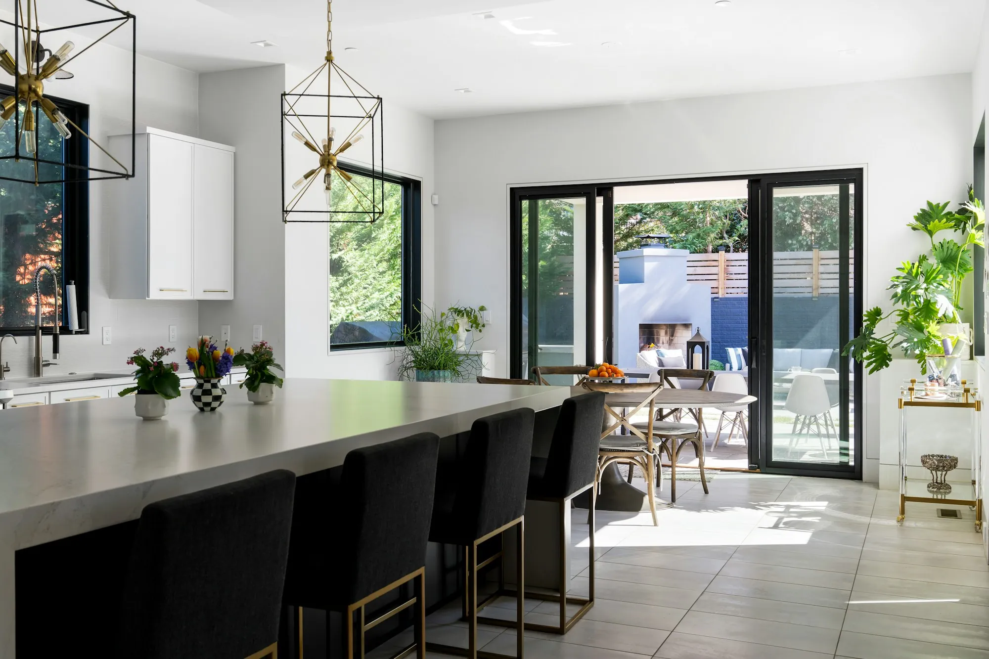 Open kitchen with a long island, black stools and doors out to a patio