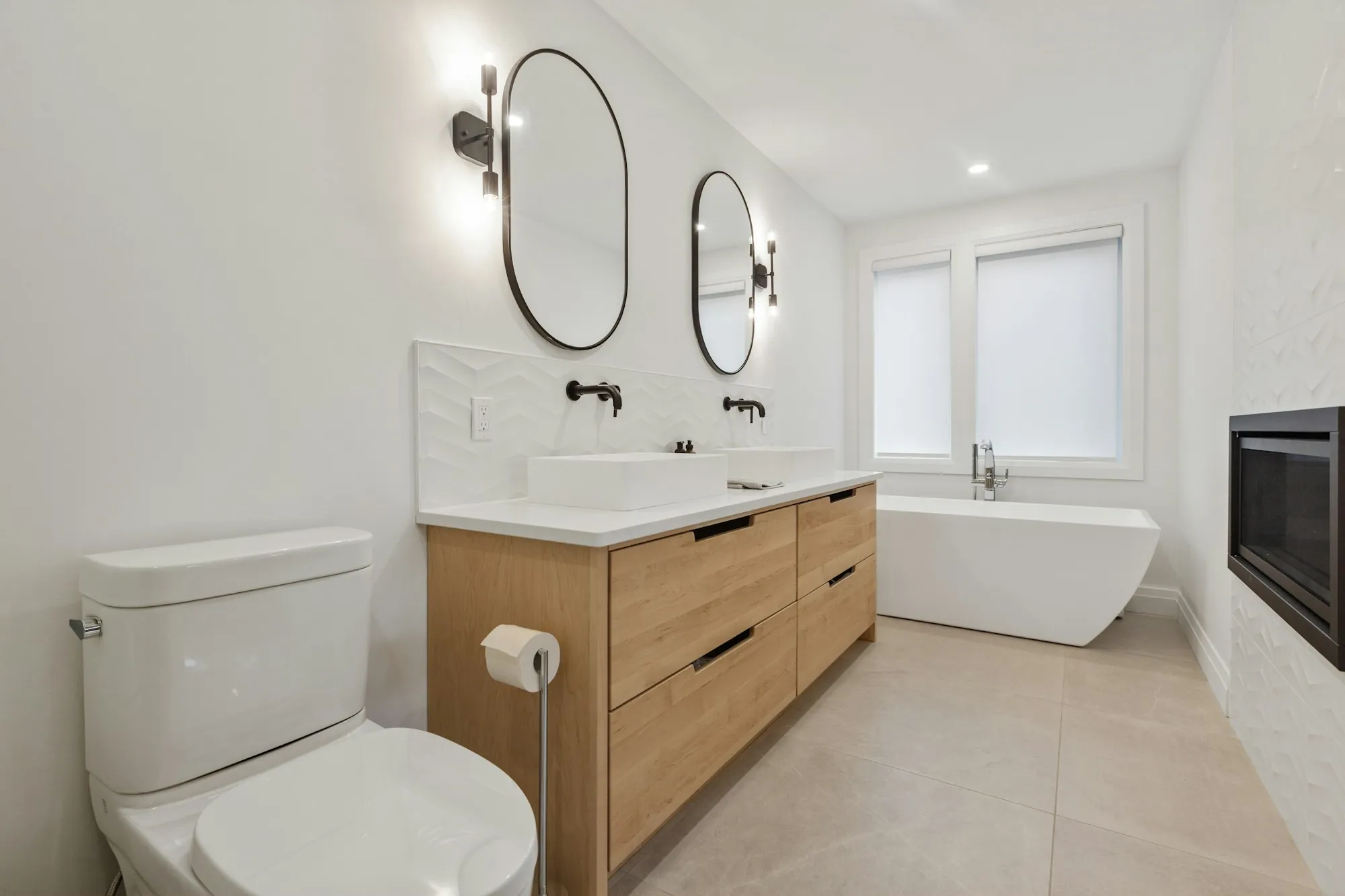 Bathroom with a wood vanity, oval mirrors and a freestanding tub