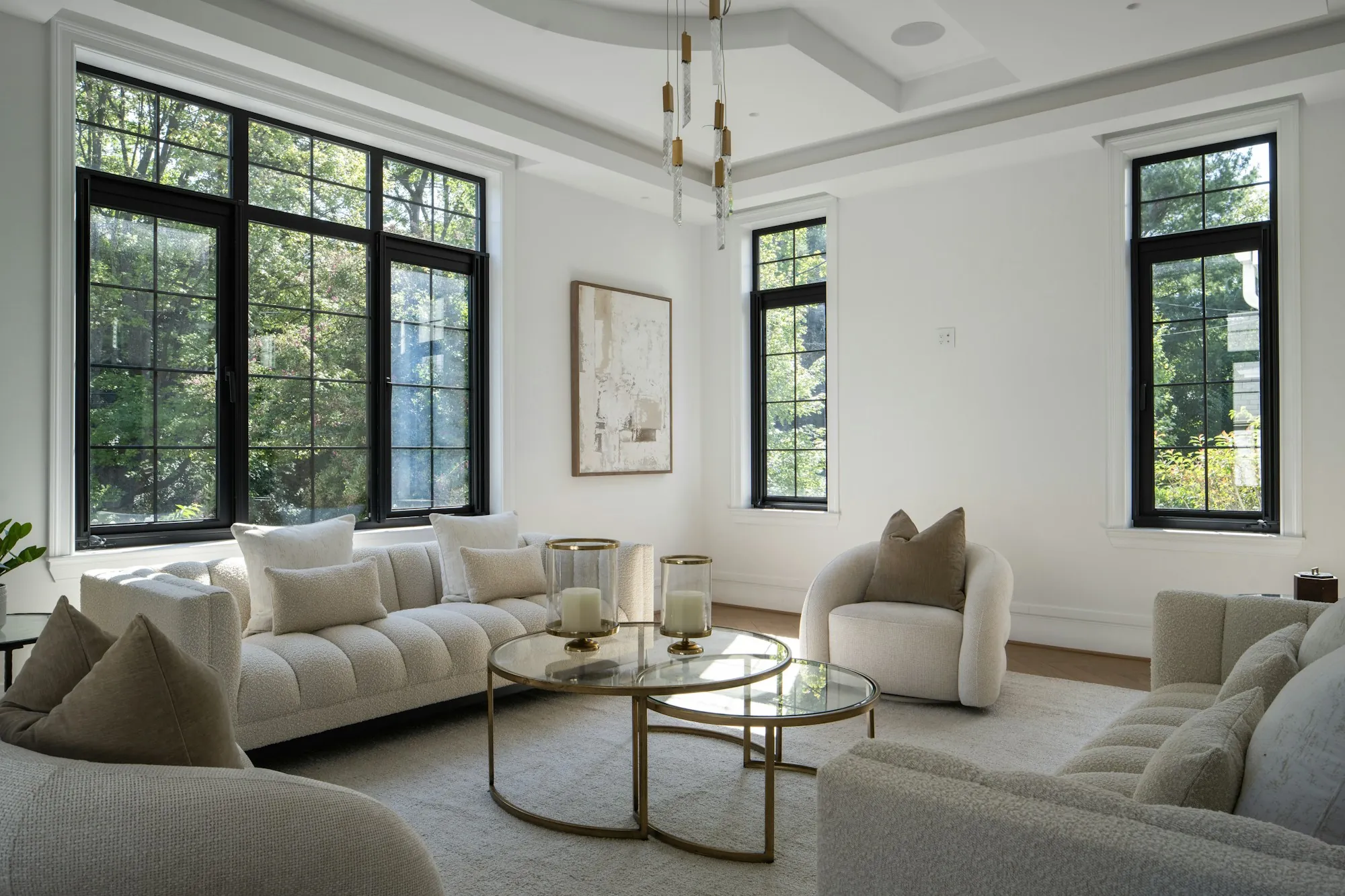 Bright living room with black-framed windows and cream sofas around glass coffee tables